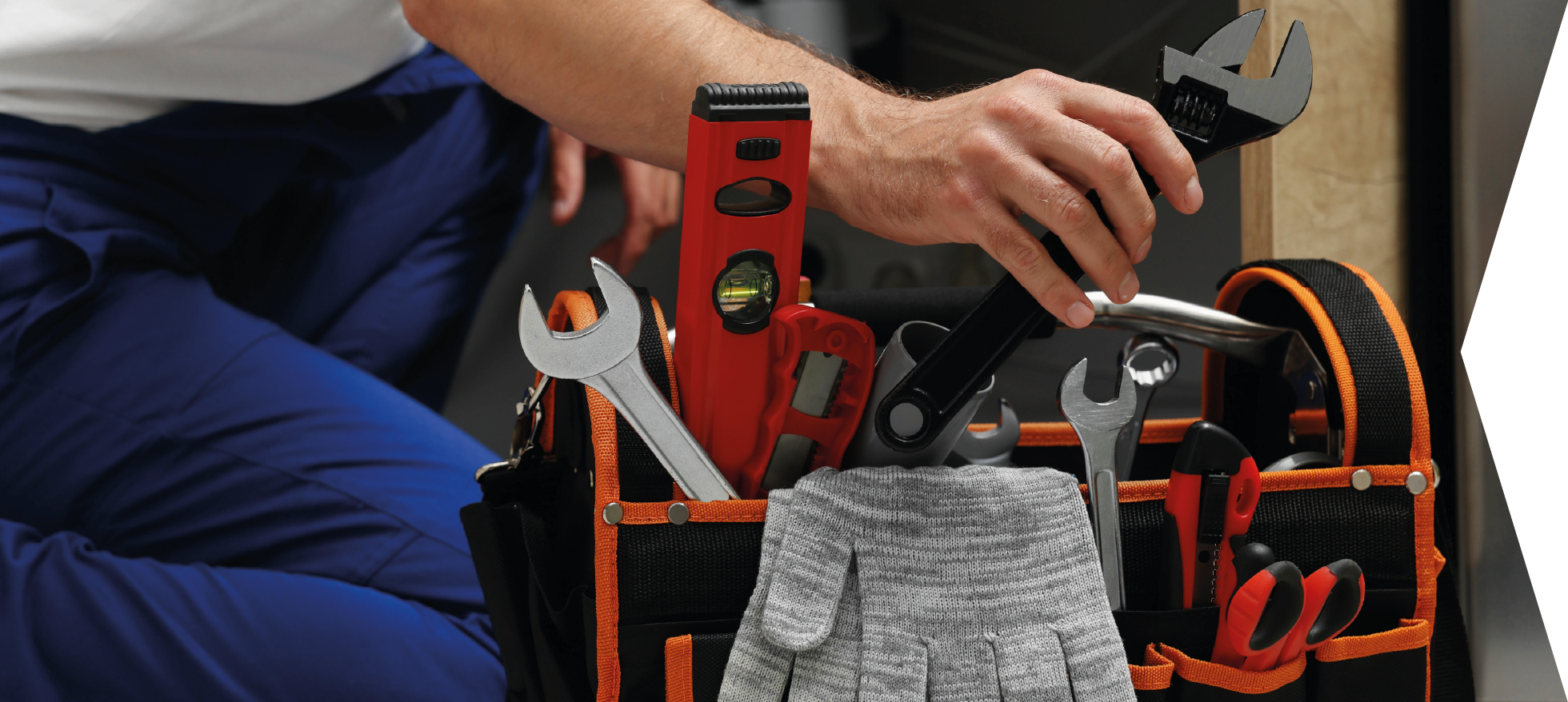 Ein Handwerker greift in seine Werkzeugtasche.