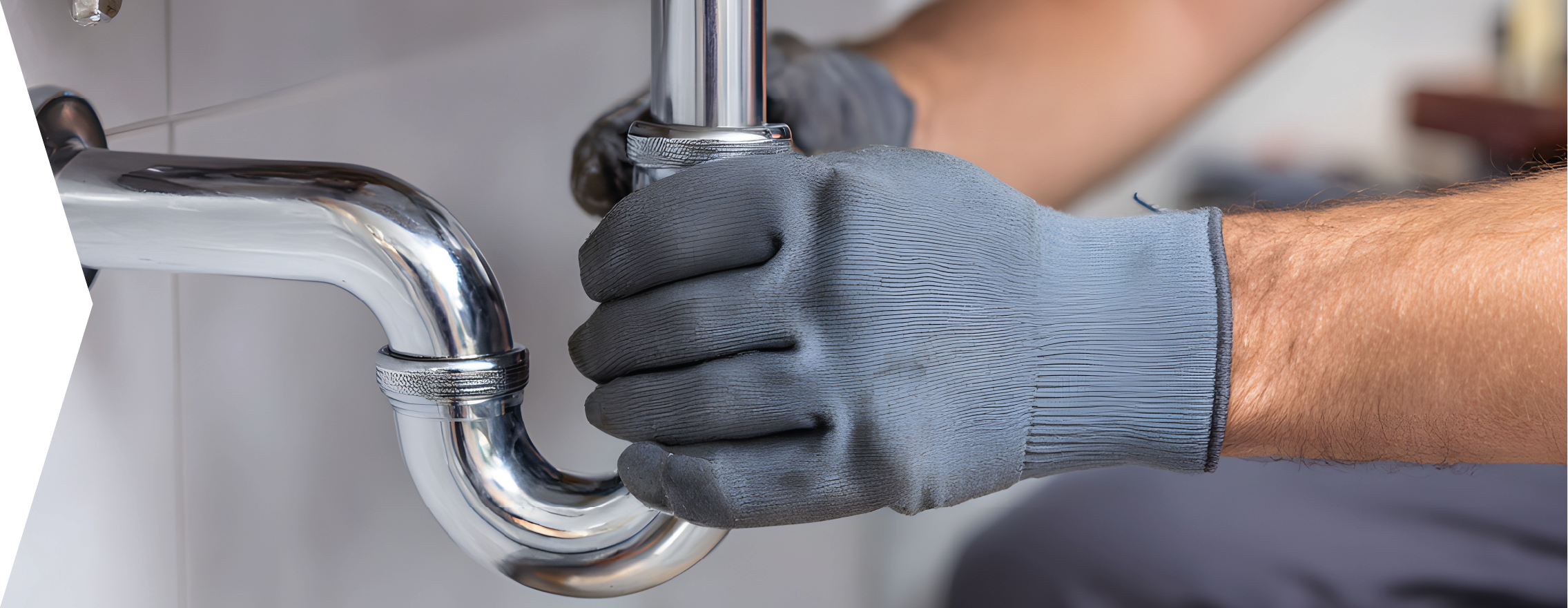 Ein Klempner mit grauen Handschuhen repariert ein Abflussrohr.